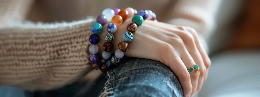 a person wearing a variety of colorful gemstone bracelets on their wrist, looking relaxed and peaceful.