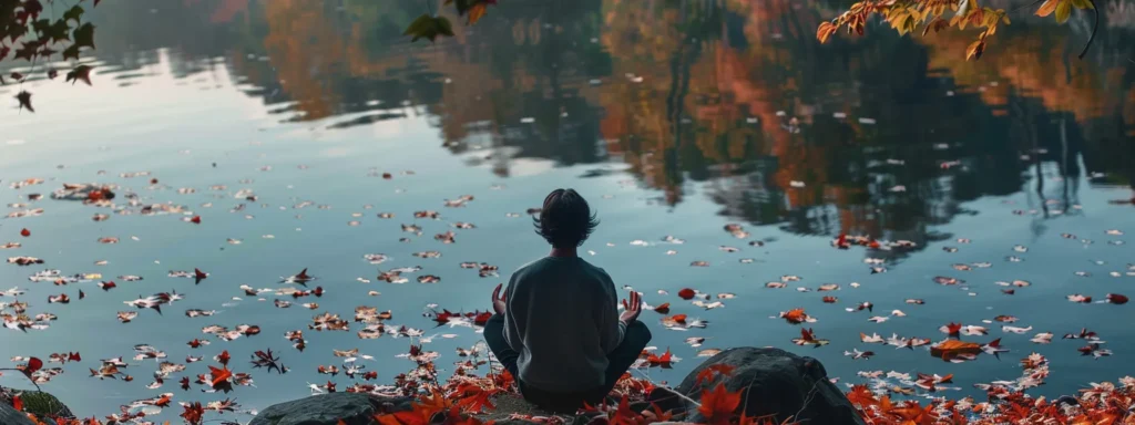 a person sitting peacefully by a tranquil lake, surrounded by colorful autumn leaves, practicing heartmath interventions to unlock trauma recovery.