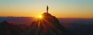 a person standing confidently on top of a mountain peak, gazing out at a breathtaking sunrise.