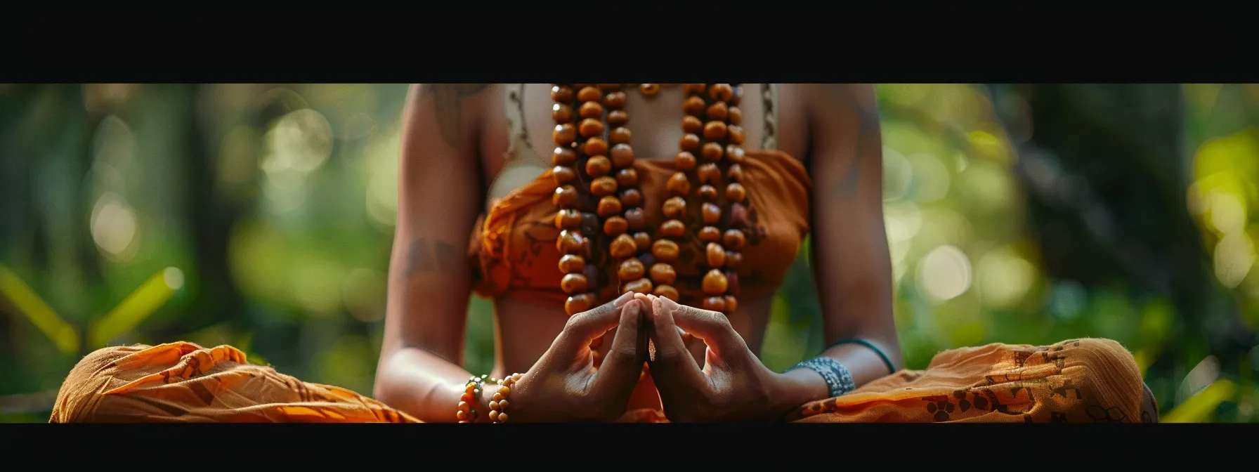 a person wearing a necklace adorned with vibrant rudraksha beads, peacefully meditating in a serene natural setting.